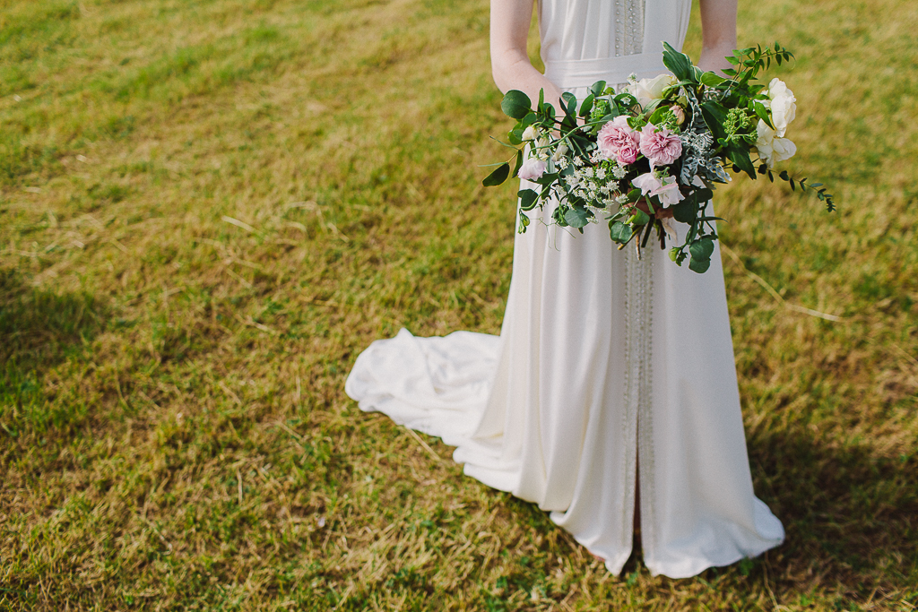 Wild escaping rose bouquet held by a festival wedding bride in a Worcestershire field! Tuckshop Flowers. Photo Sara Lemon