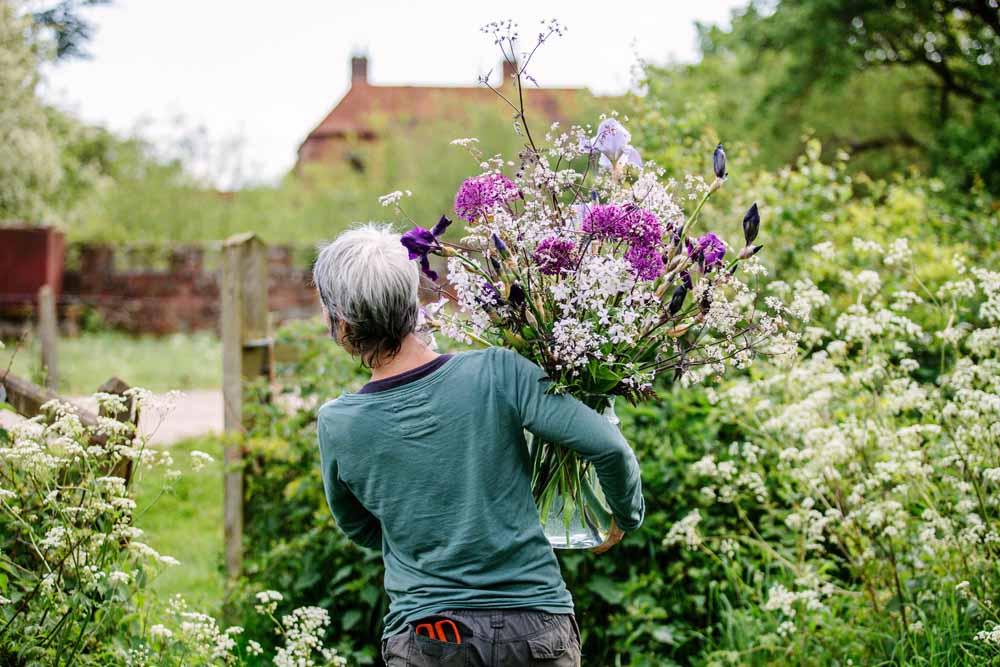Rachel of Green and Gorgeous carries a bucket brimming with freshly cut frothy white ammi back to the workshop on her flower farm.