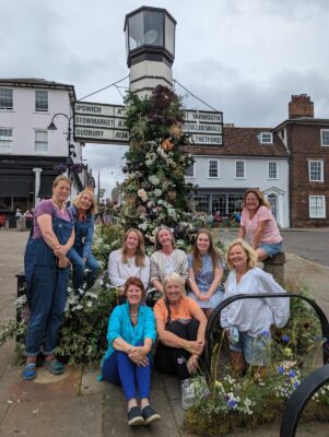 East Anglia members gather in Bury St Edmunds to decorate the landmark signpost with locally grown cut flowers for British Flowers Week 2023