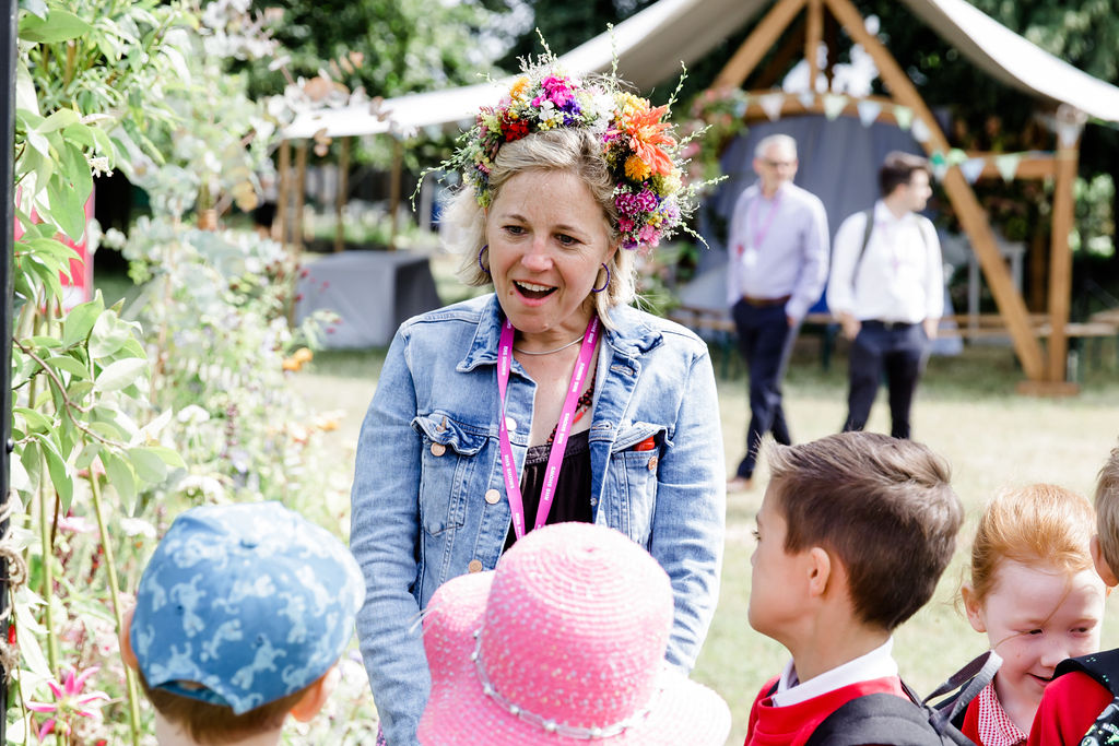 Char Johnson, wearing a flower crown, chats to school children and inspires them to embrace flowers at RHS Hampton Court.