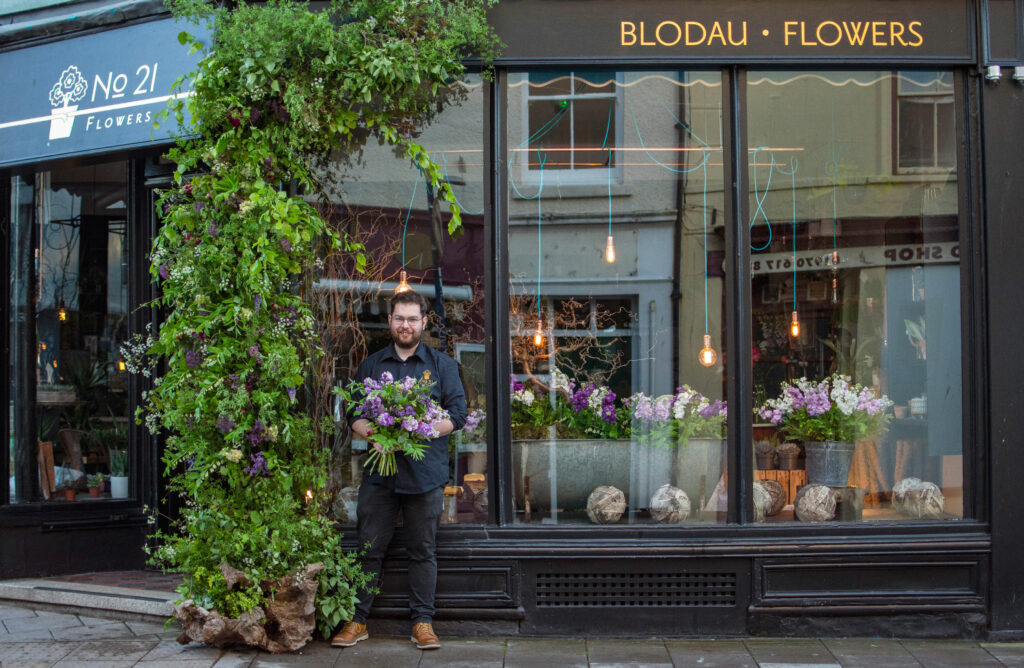 Alex of Number21 Flowers decorates his shop window with British flowers in celebration of British Flowers Week 2021