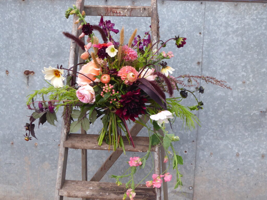 A gorgeous bouquet of locally grown British flowers by Quirky flowers, Staffordshire, stands on an old stepladder. Full of scented roses, dahlias, grasses and unusual seasonal ingredients.
