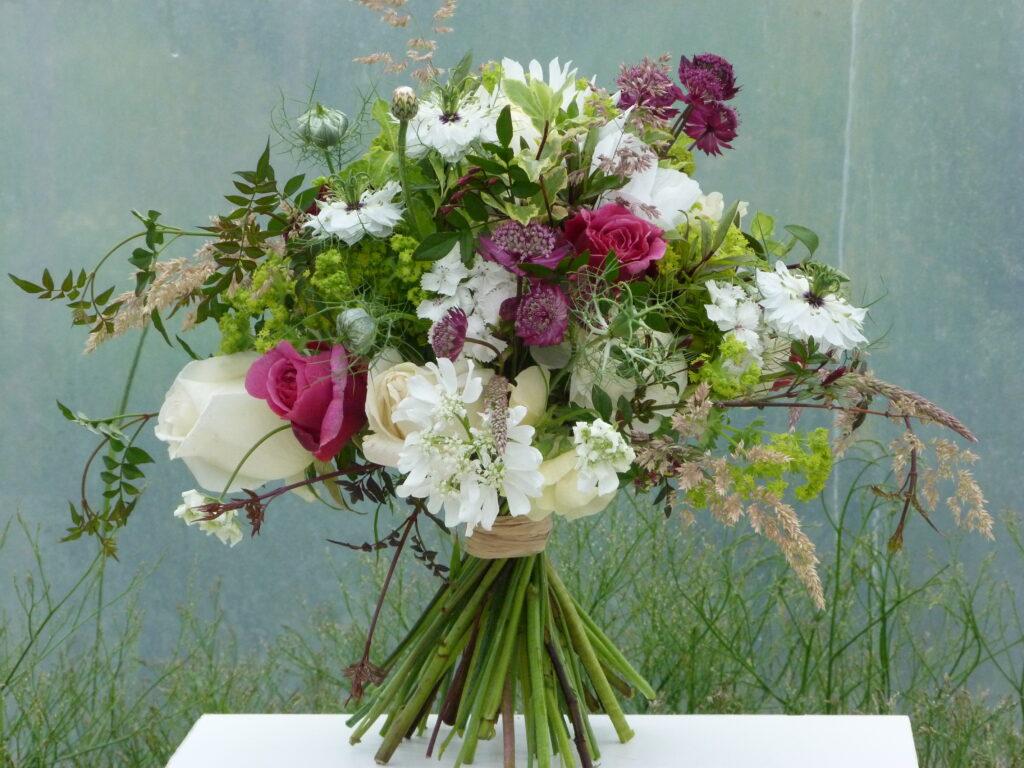 A beautiful early summer wedding bouquet with pops of pink amongst white flowers by The Sussex Cutting Garden