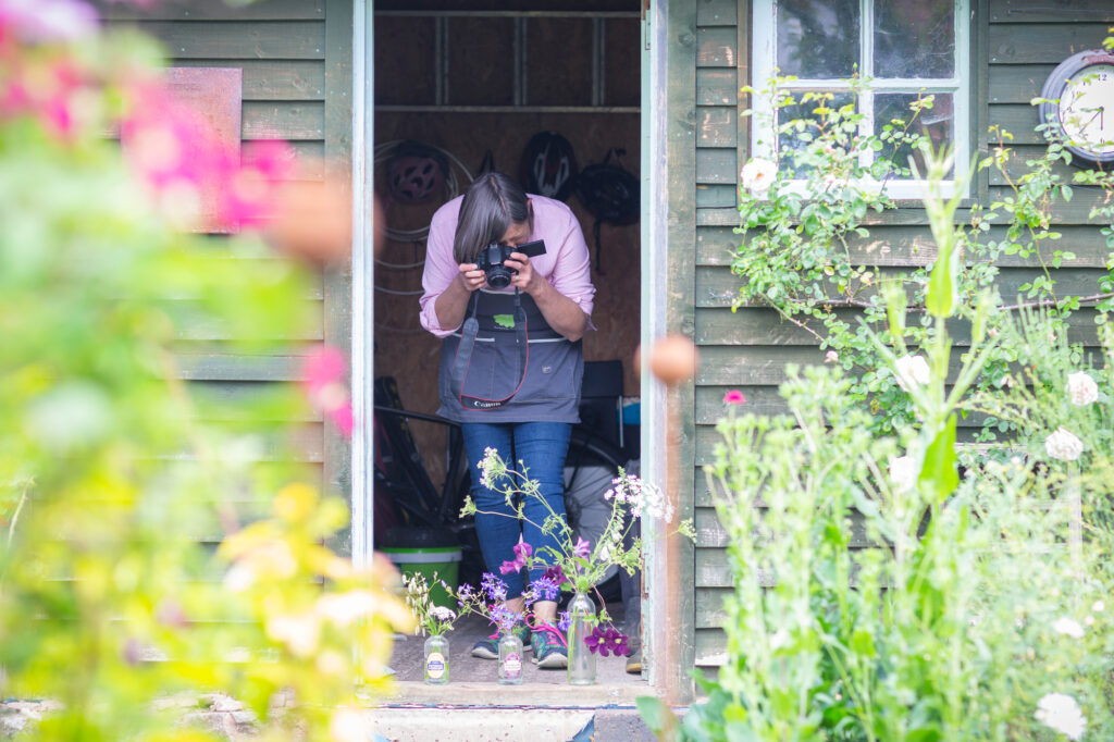 Her business allows Carole to combine her love of growing, flowers and photography. Here she's taking photos of arrangements on her workshop doorstep.