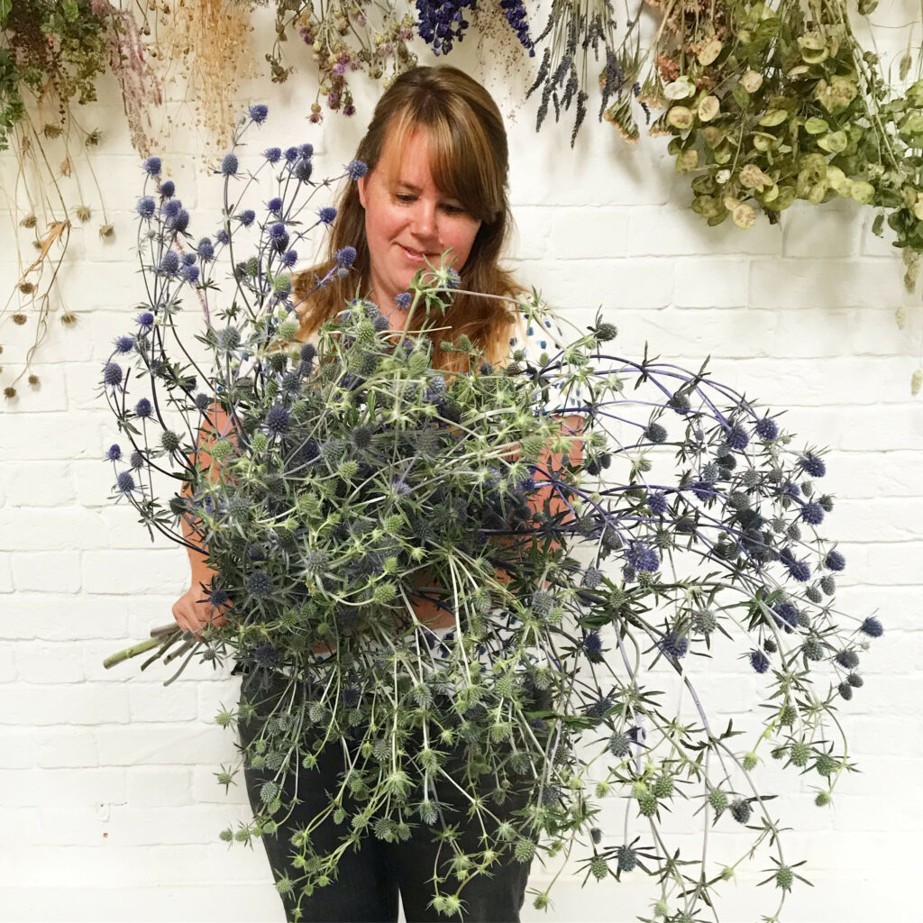 Sacha of the Floral Potager holds a huge bunch of silvery blue eryngiums in her workshop