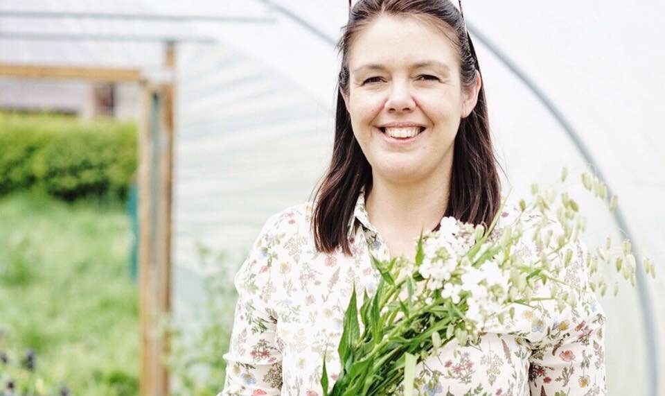 Clare of The Flower Farm holds a bunch of scented white sweet rocket as she cuts British flowers in her polytunnel for her wedding work.