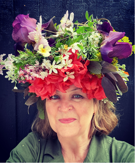 Queenie's Floral Design owner, Gretel Cooper wears an exuberant bright flower crown with red acer leaves, foliage and purple flowers.